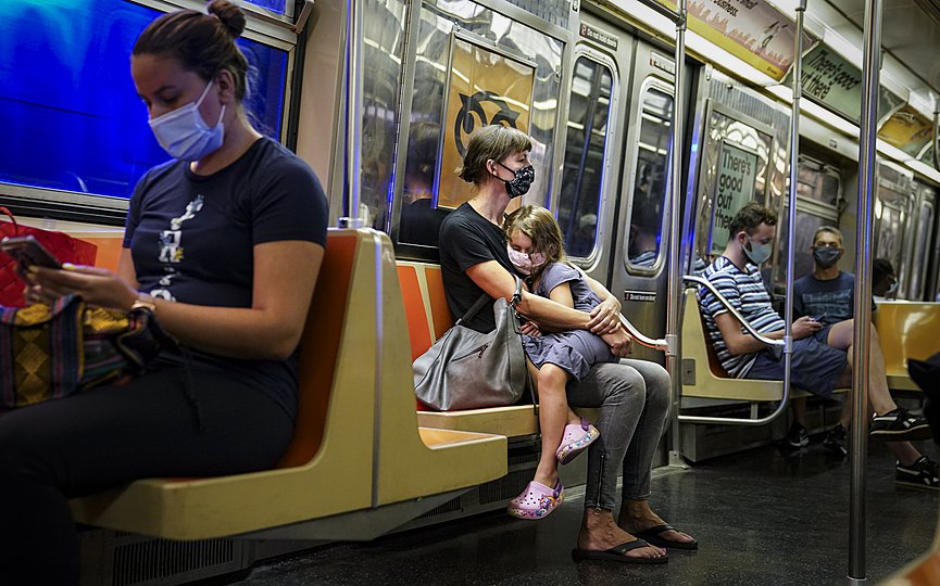 Ένα μικρό παιδί κάθεται στην αγκαλιά της μητέρας του στο μετρό της Νέας Υόρκης. (AP Photo/John Minchillo)